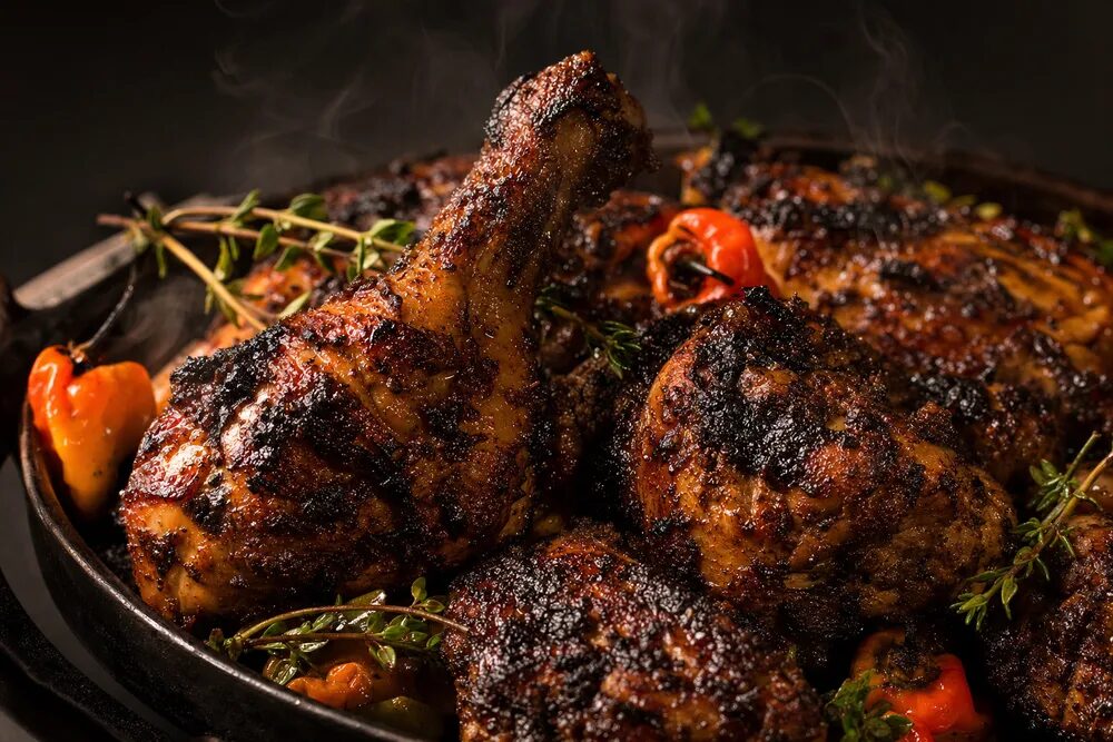 Charred jerk chicken pieces in a cast iron pan.